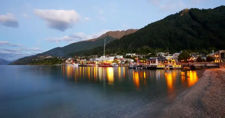 Queenstown waterfront at dusk beneath forested mountains, New Zealand