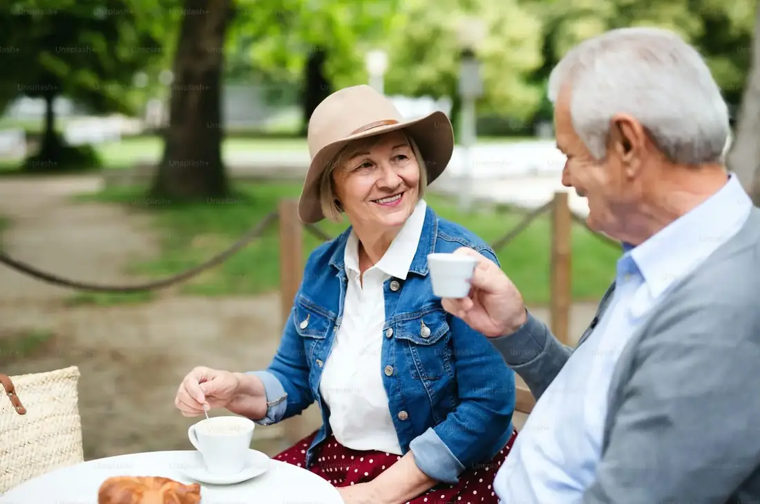 Senior couple smiling at each other over coffee in a park café