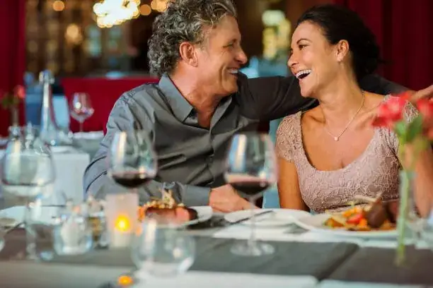 Mature couple laughing together over dinner at an elegant restaurant