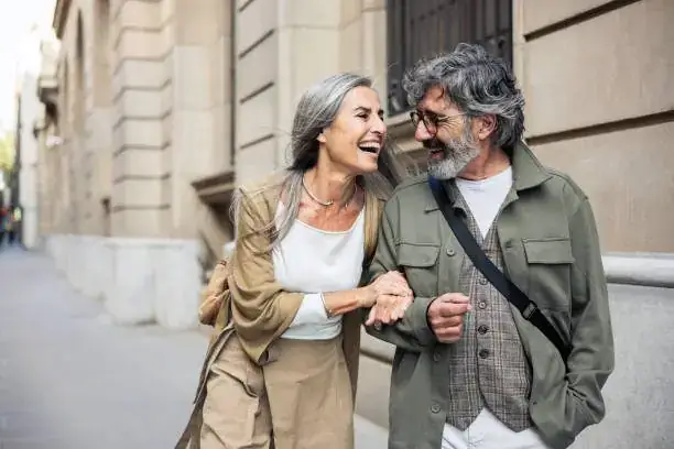 Elegant mature couple in their sixties laughing together while walking through a city