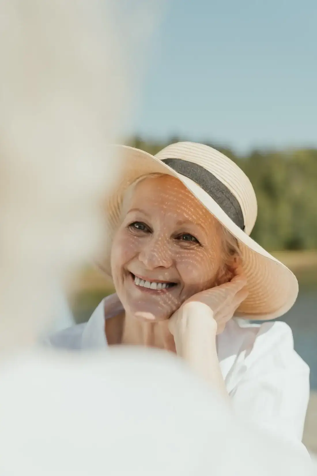 Elegant mature woman in a sun hat smiling warmly outdoors