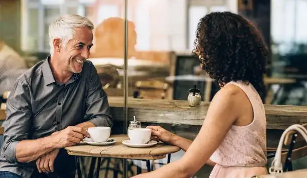 Mature couple laughing together over coffee at a café table